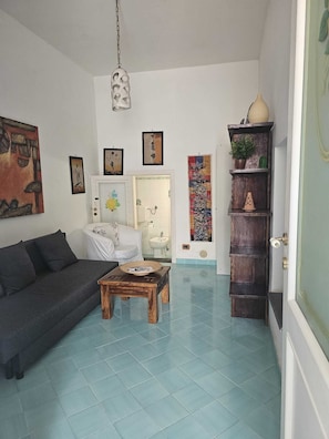 A living room with a sofa, coffee table, and artwork on the walls. - THE HOUSE IN THE CATHEDRAL VIETRI SUL MARE (Vietri sul Mare)