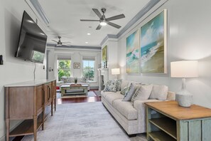 A living room with a flat-screen TV, ceiling fan, and artwork on the walls. - Retreat at Savannah Harbor 30+ Night Stay (Savannah)