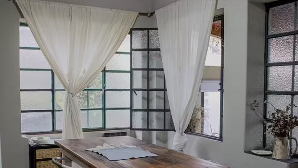 Ein Essbereich mit einem Holztisch, weißen Stühlen und einem Fenster mit satinierten Scheiben.