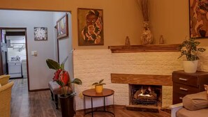 Ein Wohnzimmer mit Kamin, einer Couch, einem Couchtisch und einem Essbereich im Hintergrund.