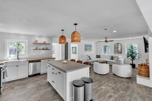 A spacious kitchen with white cabinets, a central island, and pendant lighting. - The Crescent by Duncan Real Estate (Anna Maria)