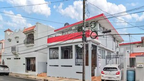 Un bâtiment à deux étages, avec un toit rouge, une façade blanche et une entrée fermée par un portail.