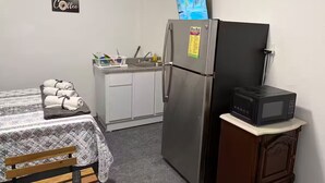 Une petite cuisine équipée d’un réfrigérateur, d’un four à micro-ondes et d’une petite table avec des serviettes.