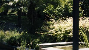 Terraza de madera con jardinera de piedra y una pequeña cascada.