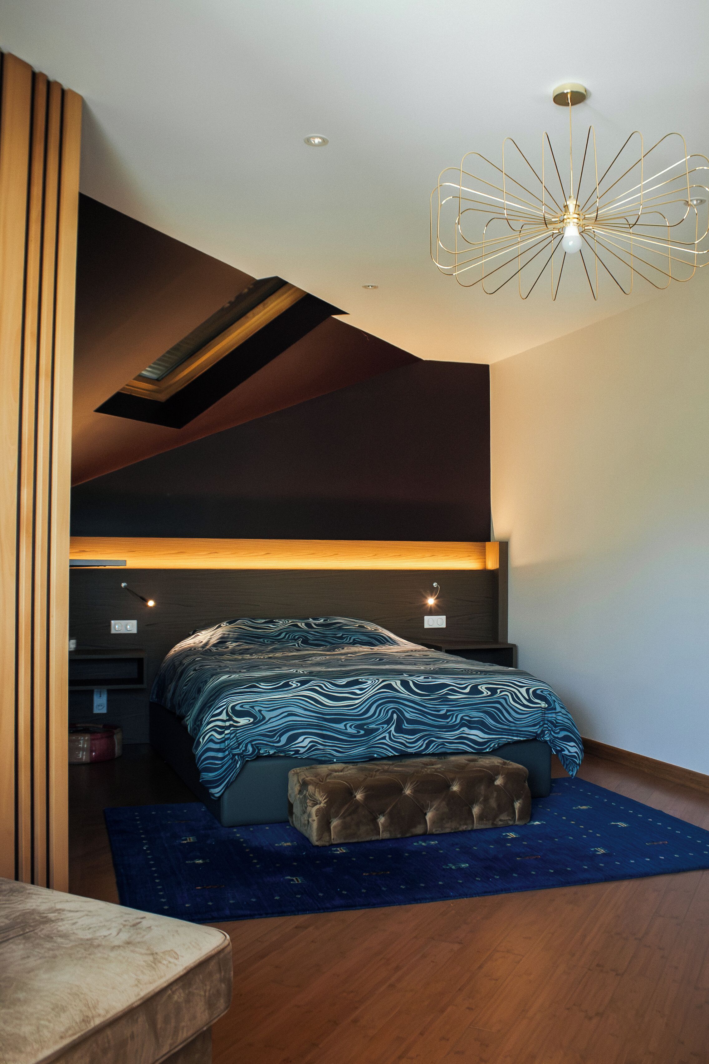 A modern bedroom with a bed, a unique ceiling light, and a built-in bench.