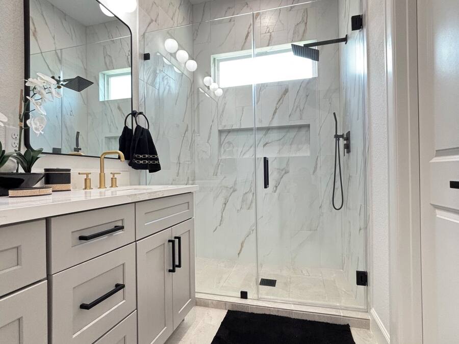 A modern bathroom with a vanity, mirror, and shower.