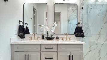 A modern bathroom with a double vanity, marble backsplash, and a black rug.