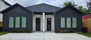 A modern two-story house with a dark exterior, a central entrance, and a visible address number.