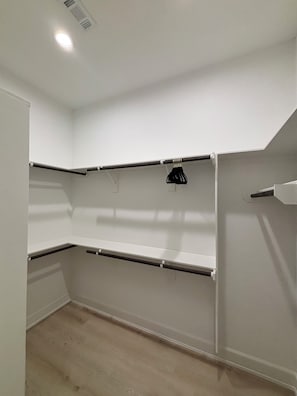A room with white walls, a wooden floor, and built-in shelving units.