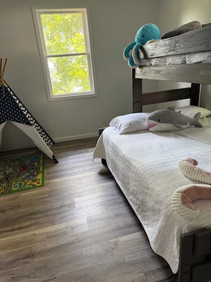 A bedroom with a bunk bed, a window with daylight, a star-patterned curtain, a map rug, and a plush shark toy. - Deer Run on Eddy Bay
4 bd , 3 bath luxury lake living! (Eddyville)