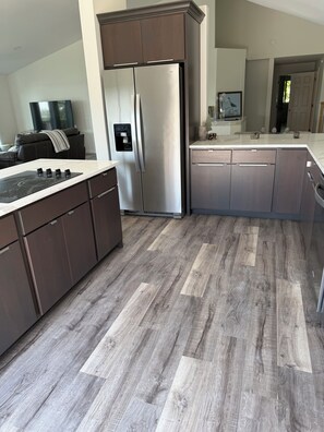 A modern kitchen with a stainless steel refrigerator, dark cabinetry, and a wood-patterned floor. - Deer Run on Eddy Bay
4 bd , 3 bath luxury lake living! (Eddyville)