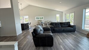 A spacious living area with a sectional sofa and a dining table, large windows, and a high ceiling. - Deer Run on Eddy Bay
4 bd , 3 bath luxury lake living! (Eddyville)