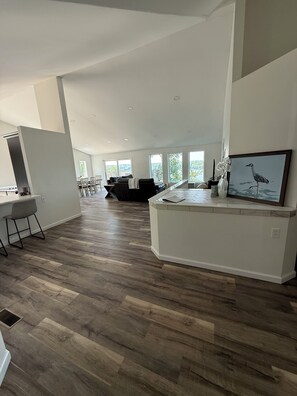 Uma sala de estar ampla com ilha de cozinha, área de jantar e grandes janelas que proporcionam muita luz natural.