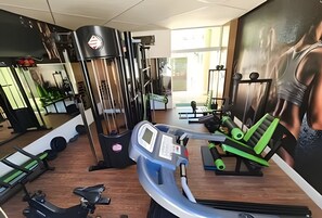Ett gym med träningsutrustning, speglar och ett stort fönster.