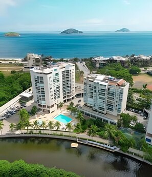 Un hôtel de grande hauteur, avec de nombreux étages, une piscine et une vue sur l’océan.