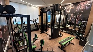 Un gimnasio con equipo de ejercicio, una cinta de correr y un muro de espejos.