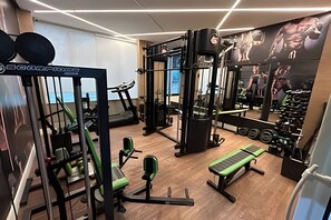Un gimnasio con equipo de ejercicio, una cinta de correr y un muro de espejos.
