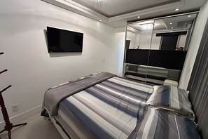 Une chambre à coucher avec un lit, une télévision, un miroir et une armoire.
