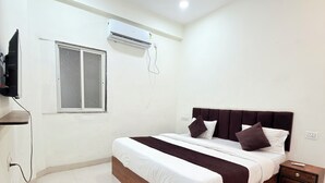 Une chambre à coucher comprenant un lit, une table de chevet, un téléviseur et un appareil de climatisation.