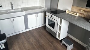 A modern kitchen with white cabinets, a stainless steel stove, and a wooden countertop. - Charming, cosy T2 in the heart of Caen - Free parking (Caen)