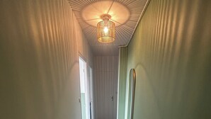 A hallway with a carpeted floor, a ceiling fan, and a light fixture. - Charming, cosy T2 in the heart of Caen - Free parking (Caen)