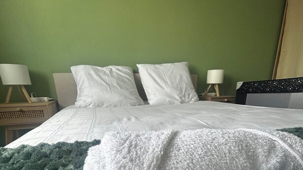 A neatly made bed with white linens and a green throw blanket, two bedside lamps, and a nightstand with a lamp. - Charming, cosy T2 in the heart of Caen - Free parking (Caen)