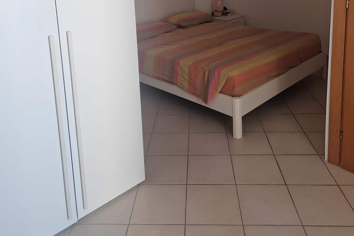 A bedroom with a bed, a nightstand, and a wardrobe.