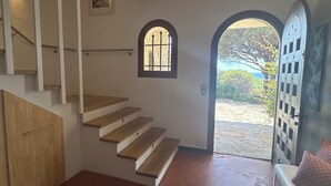 A staircase leading to a landing with a small window and a door opening to a garden. - Le Mas des 3 Frères - sea view - 200m walk to the beach - Domaine de l'Escalet (Ramatuelle)