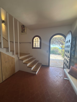 Eine Treppe führt zu einer Zwischenebene mit einem kleinen Fenster und einer Tür, die in einen Garten hineinführt.