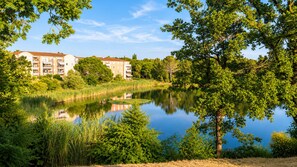 Una vista tranquila de un lago con un edificio de varios pisos al fondo.