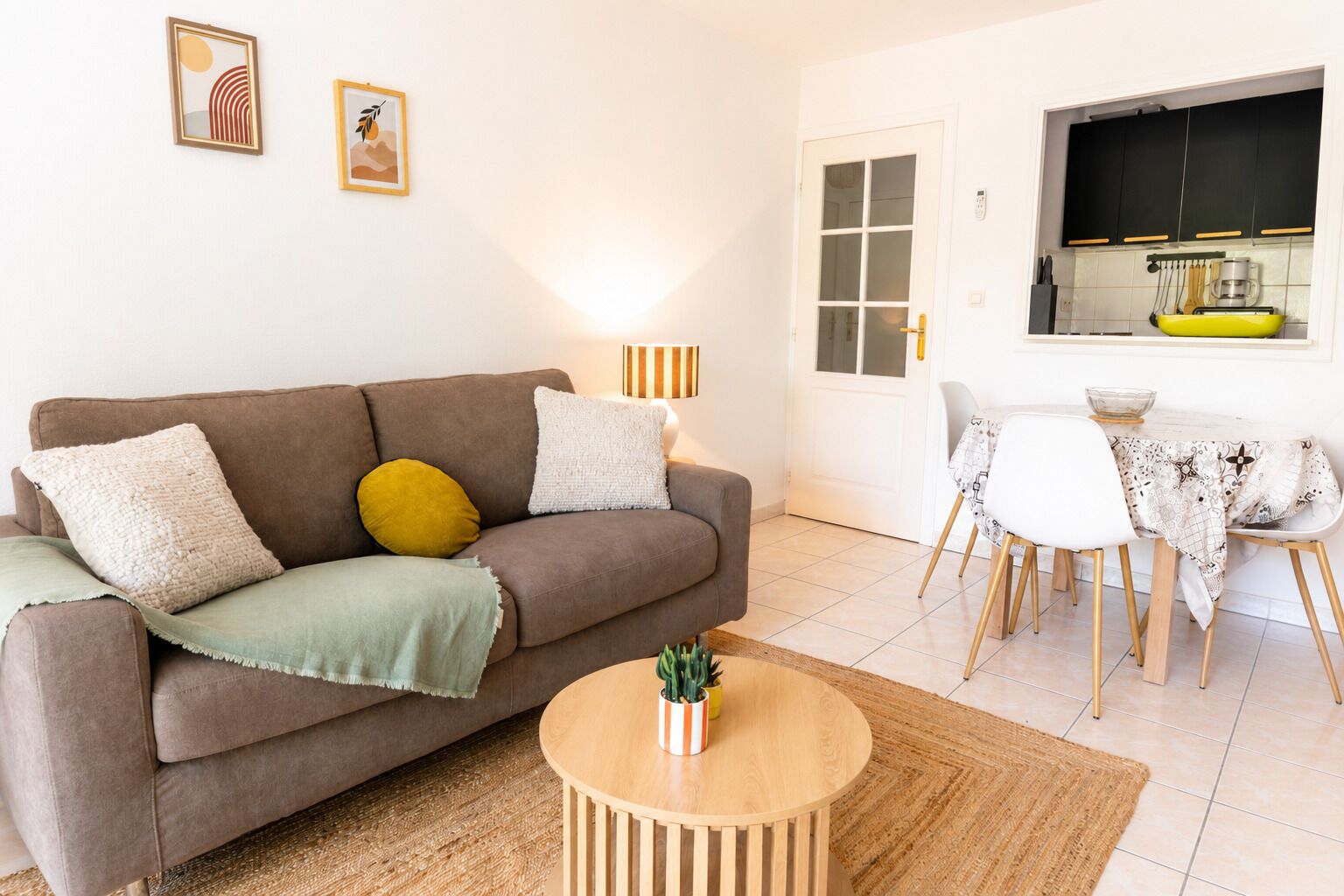A living room with a sofa, a round wooden coffee table, and a dining area with a table and chairs.