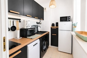A compact kitchen with a microwave, toaster, coffee maker, and a washing machine. - Cosy T2 with pool, beach 8 min away! (Fréjus)