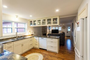 A modern kitchen with white cabinetry, a granite countertop, a dishwasher, and a refrigerator. - Welcome to MapleWoods! 30 second walk to the Beach! Pet Friendly! (Innisfil)