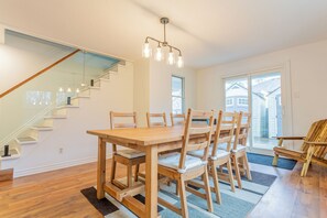 A dining area with a wooden table and chairs, a staircase, and a view through a glass door. - Welcome to MapleWoods! 30 second walk to the Beach! Pet Friendly! (Innisfil)