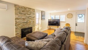 Ein Wohnzimmer mit Steinwand, Kamin, großem Flachbildfernseher und Ecksofa.