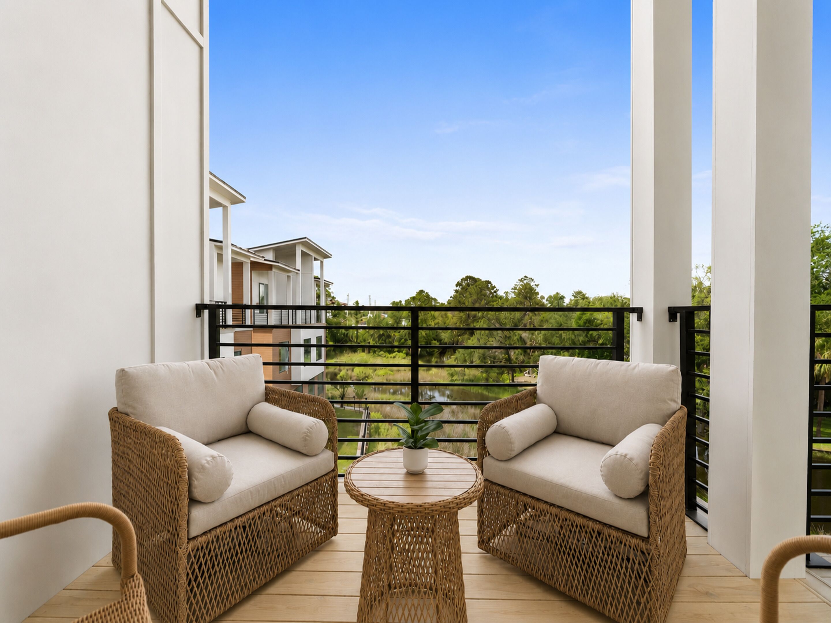 A balcony with wicker furniture, a round table, and a view of a building and greenery.