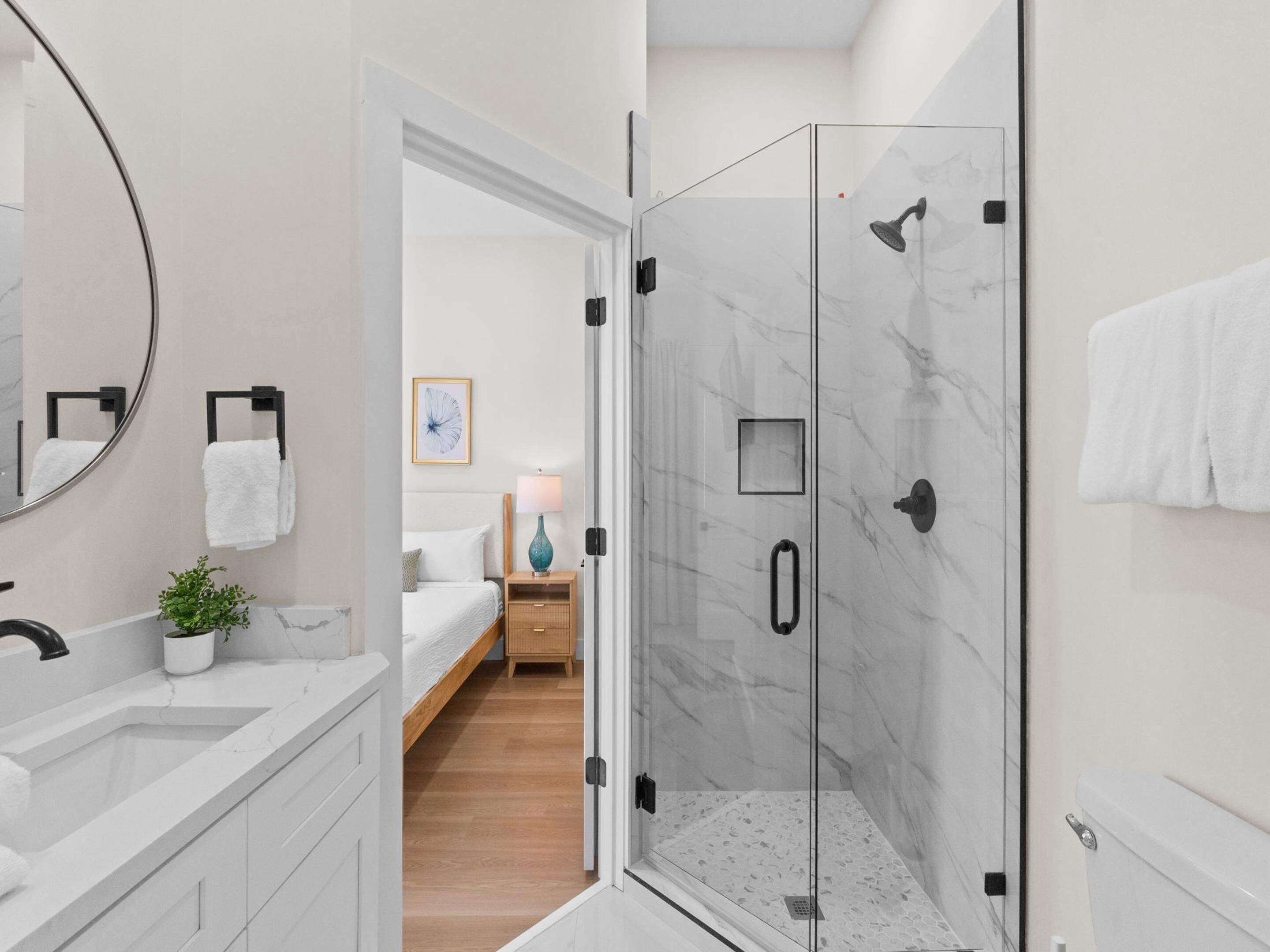 A modern bathroom with a glass shower enclosure, a sink, and a mirror.