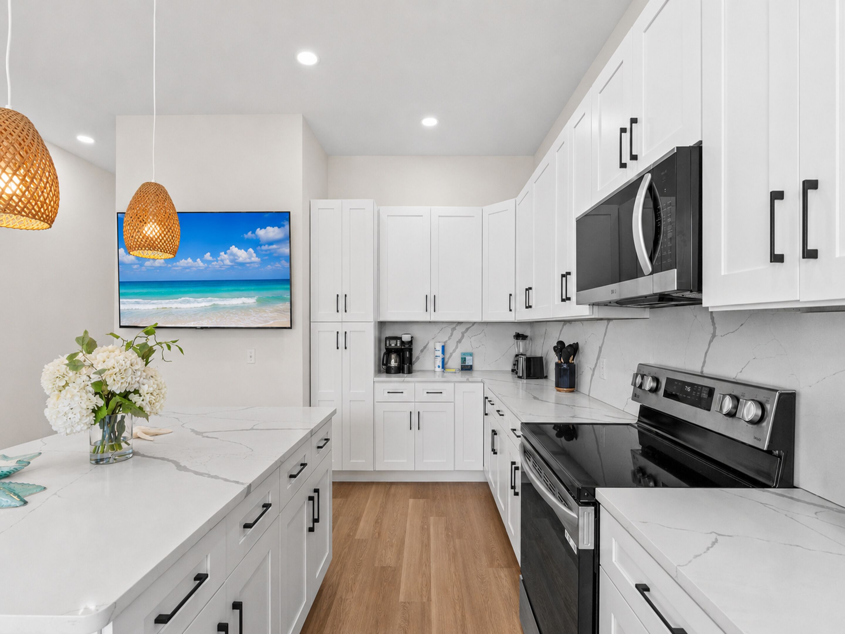 A modern kitchen with white cabinets, a black microwave, and a stainless steel oven.