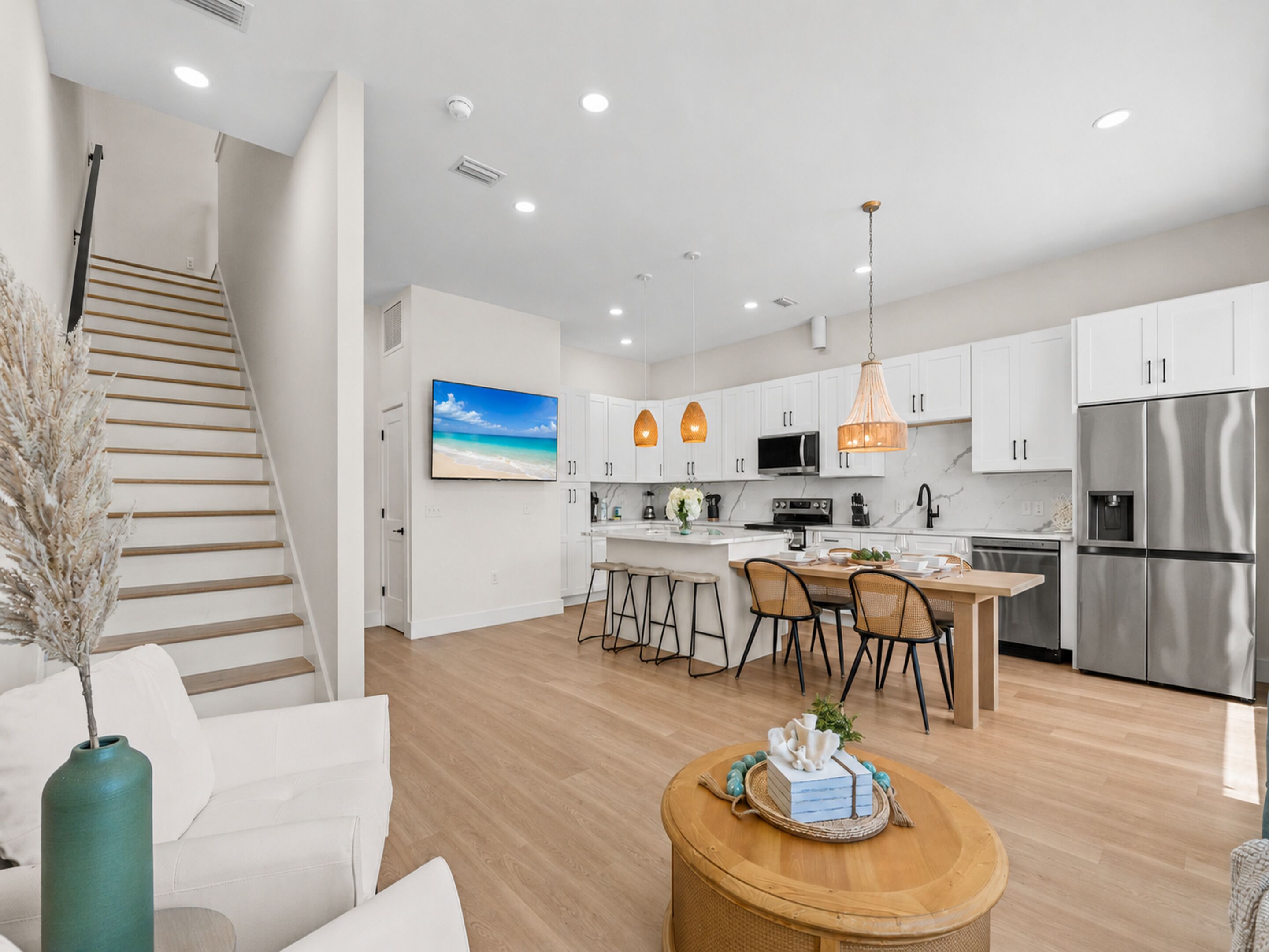 A modern kitchen with white cabinets, stainless steel appliances, and a wooden dining table.
