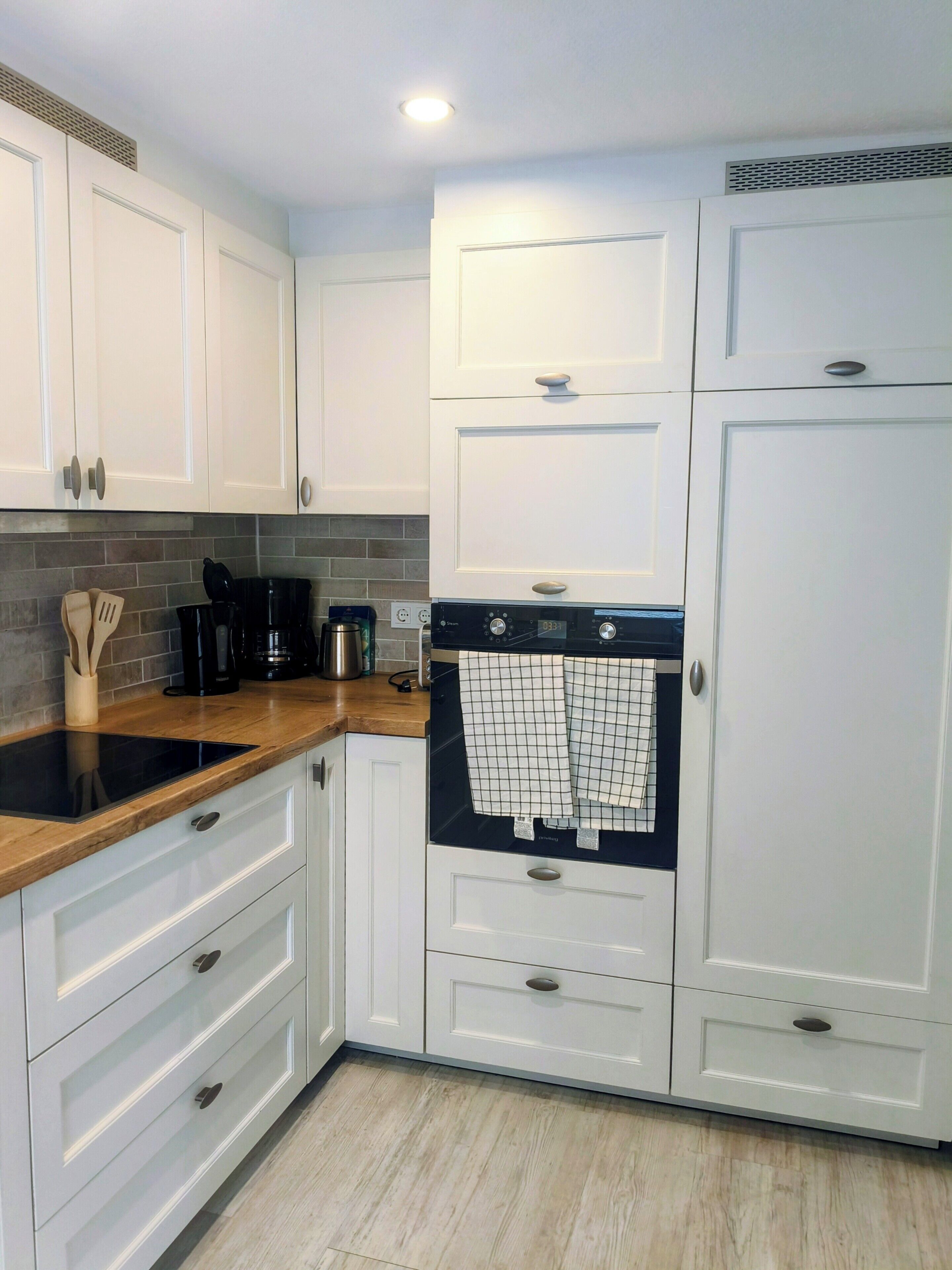Una cocina moderna con armarios blancos, una estufa negra y una cafetera.