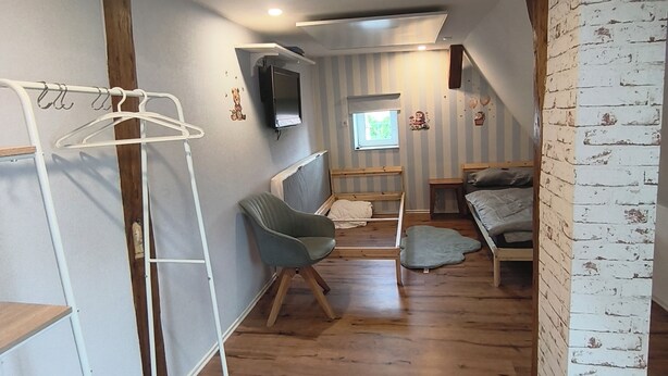 A room with a bunk bed, a chair, a TV mounted on the wall, and a window. - Vacation cottage Obermarchtal (Obermarchtal)