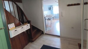 A staircase leading to a second floor, a dining area with chairs and a table, and a hallway with a light fixture. - Vacation cottage Obermarchtal (Obermarchtal)