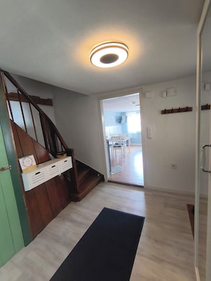 A staircase leading to a second floor, a dining area with chairs and a table, and a hallway with a light fixture.