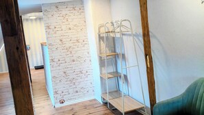 A room with wooden flooring, a green chair, a metal shelf unit, and a brick-patterned wall. - Vacation cottage Obermarchtal (Obermarchtal)