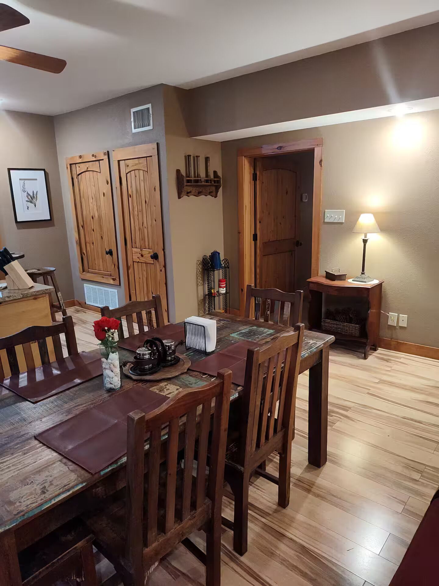 A dining area with a wooden table, chairs, and a ceiling fan.