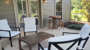 A patio with outdoor furniture, a wooden table, and two bar stools. - The Farm House at Bliss Point Ranch FM-17 (Grand Saline)