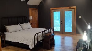 A bedroom with a bed, a ceiling fan, a wooden door, and a window. - The Farm House at Bliss Point Ranch FM-17 (Grand Saline)