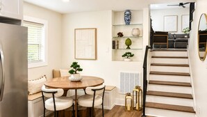 Une cuisine moderne avec un coin repas, un escalier et un salon comprenant un canapé et une table basse.