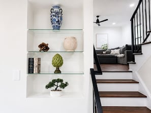 A staircase with wooden steps and black railings, leading to a living area with a gray sofa and a plant. - Spacious 4-bedroom house near LoSo Charlotte with fenced backyard (Charlotte)
