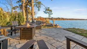 Un patio al aire libre con una mesa de piedra, sillas y una chimenea.